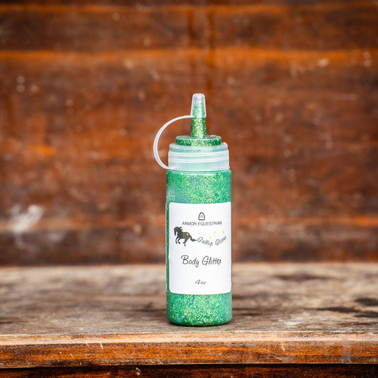 Green glittery body glimmer bottle on a wooden surface with a rustic background